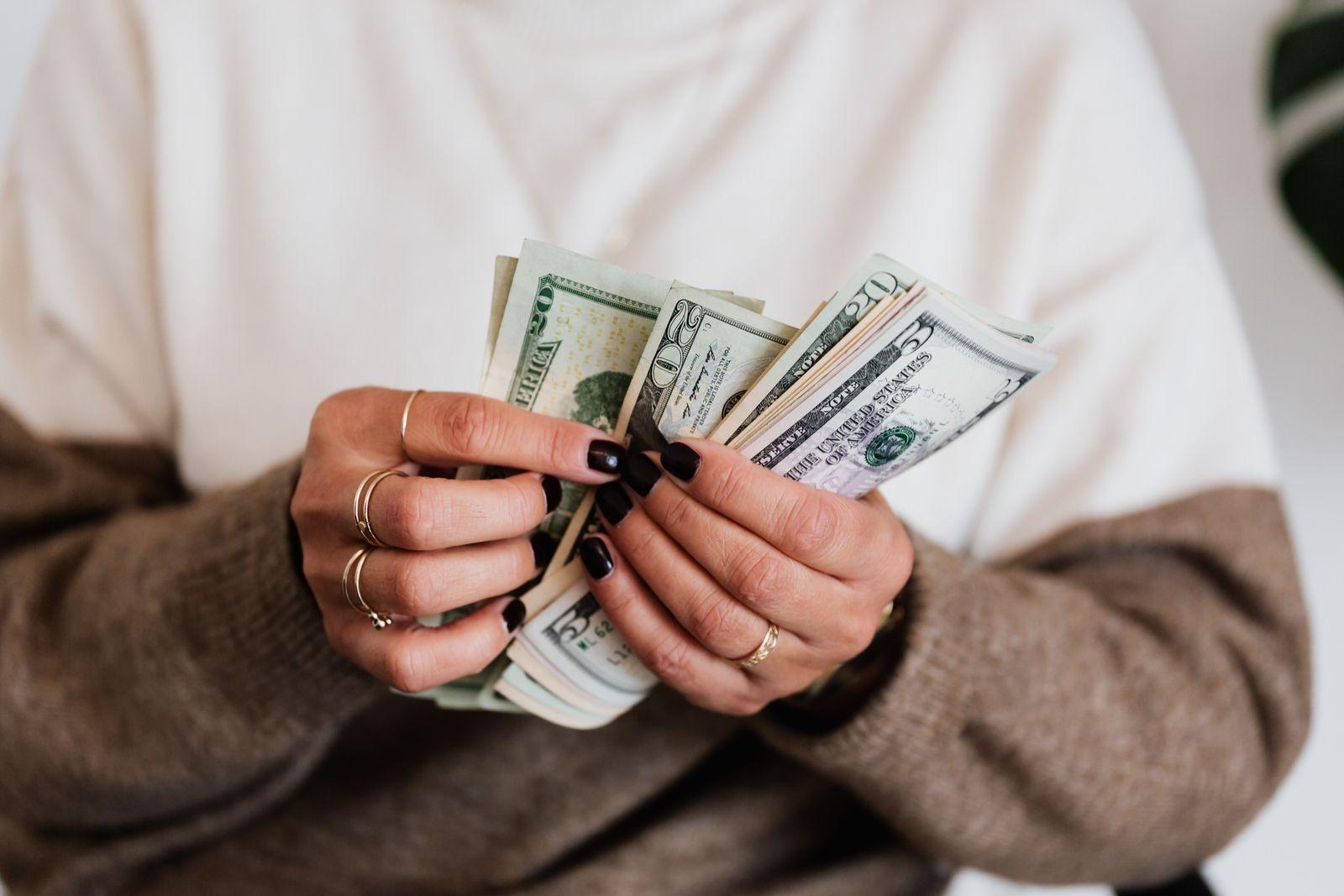 Unas manos cuentan un fajo de billetes de dólar.